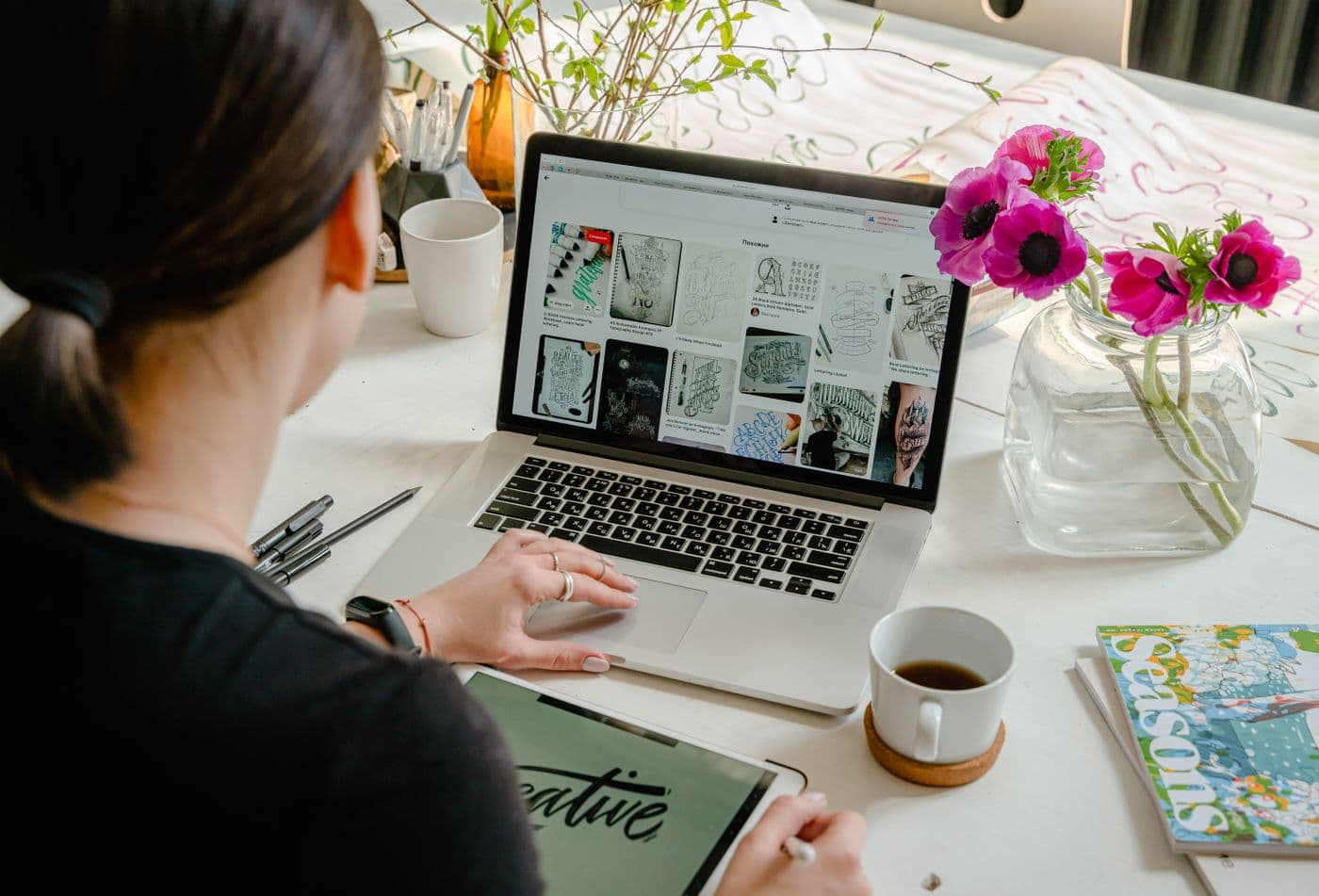A woman working on a laptop at a bright desk with flowers
